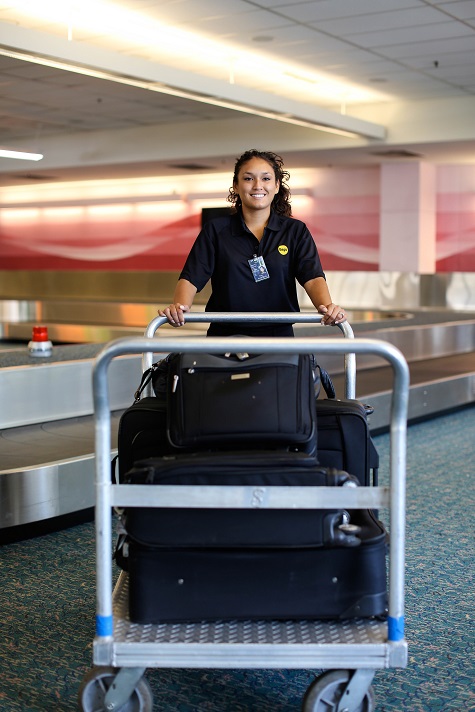 airport worker loading luggage in trolley